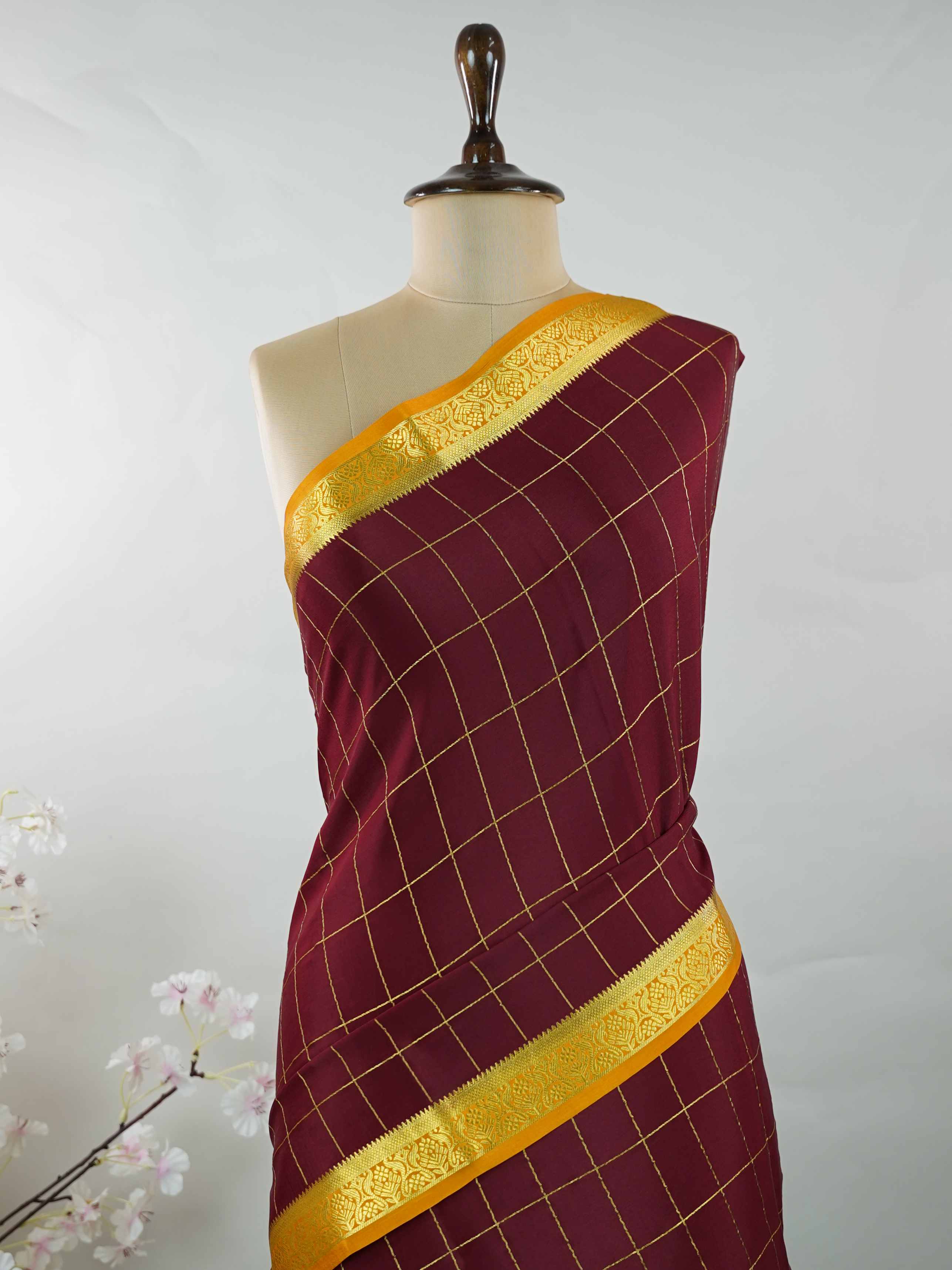 Mysore silk Pure Mysore silk in a rich maroon hue, complemented by classic checks woven gracefully across the body.br
Paired with a vibrant mustard yellow contrast, this weave exudes timeless charm and quiet sophistication. Vilasini - Maroon Pure Mysore Silk Saree | Classic Checks - Manoranjitham Weaves - Handloom Store