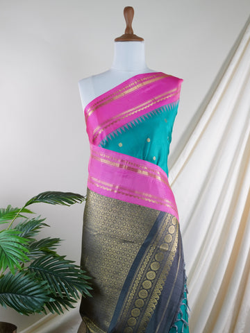 Gadwal Silk This Gadwal silk saree, adorned in Cyan and detailed with Pure Zari weaving, reflects the grandeur of Gadwal. The timeless Buttis motifs enhance its bridal charm. A perfect blend of luxury and tradition, it is designed for those who appreciate fine craftsmanship. Nattakurinji - Manoranjitham Weaves - Handloom Store