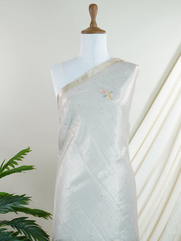 tissue This exquisite Silver Kora Tissue saree dazzles with delicate gold floral zari work, weaving elegance into every thread. Crafted on a powerloom in Varanasi, its lightweight texture shimmers beautifully, perfect for festive occasions or celebrations. The fine zari detailing adds a regal touch, blending tradition with contemporary charm. Wrap yourself in this graceful masterpiece and shine with timeless beauty. Padmalatha - Banarasi Tissue Kora Saree - Manoranjitham Weaves - Handloom Store