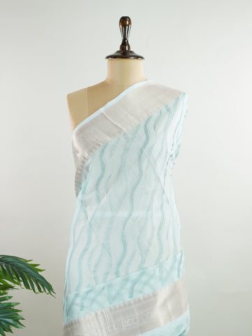 Kora This exquisite Light Blue Kora Tissue saree dazzles with delicate gold floral zari work, weaving elegance into every thread. Crafted on a powerloom in Varanasi, its lightweight texture shimmers beautifully, perfect for festive occasions or celebrations. The fine zari detailing adds a regal touch, blending tradition with contemporary charm. Wrap yourself in this graceful masterpiece and shine with timeless beauty. Nagagandhari - Manoranjitham Weaves - Handloom Store