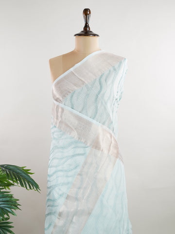 Kora This exquisite Light Blue Kora Tissue saree dazzles with delicate gold floral zari work, weaving elegance into every thread. Crafted on a powerloom in Varanasi, its lightweight texture shimmers beautifully, perfect for festive occasions or celebrations. The fine zari detailing adds a regal touch, blending tradition with contemporary charm. Wrap yourself in this graceful masterpiece and shine with timeless beauty. Nagagandhari - Manoranjitham Weaves - Handloom Store
