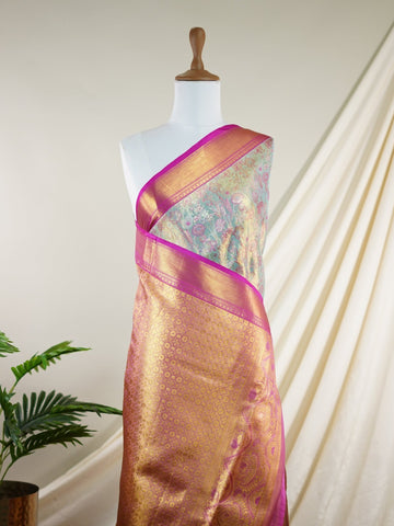 Kanchipuram Silk A sublime olive green Kanchipuram silk saree, gracefully adorned with gold and silver zari buttas, reflecting timeless artistry. The vibrant pink border lends a striking contrast, perfect for festive occasions and weddings. Woven from 100% pure silk, this saree radiates heritage and elegance in every thread.Its luxurious texture and intricate zari work make it a cherished piece for your trousseau or special celebrations.          #ManoranjithamSilks #KanjivaramHandloom #PureSilkSaree #Brida