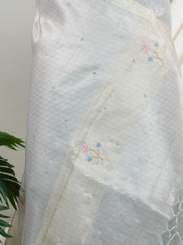 tissue This exquisite Silver Kora Tissue saree dazzles with delicate gold floral zari work, weaving elegance into every thread. Crafted on a powerloom in Varanasi, its lightweight texture shimmers beautifully, perfect for festive occasions or celebrations. The fine zari detailing adds a regal touch, blending tradition with contemporary charm. Wrap yourself in this graceful masterpiece and shine with timeless beauty. Padmalatha - Banarasi Tissue Kora Saree - Manoranjitham Weaves - Handloom Store