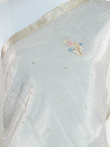 tissue This exquisite Silver Kora Tissue saree dazzles with delicate gold floral zari work, weaving elegance into every thread. Crafted on a powerloom in Varanasi, its lightweight texture shimmers beautifully, perfect for festive occasions or celebrations. The fine zari detailing adds a regal touch, blending tradition with contemporary charm. Wrap yourself in this graceful masterpiece and shine with timeless beauty. Padmalatha - Banarasi Tissue Kora Saree - Manoranjitham Weaves - Handloom Store
