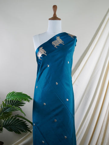 Katan A masterpiece from Varanasi, this Banarasi Katan saree in Dark Teal is a tribute to India's rich handloom legacy. The Tested Zari weaving and Motifs motifs make it a perfect choice for brides and celebrations. Every thread speaks of elegance, tradition, and the skilled hands that bring this saree to life. Sohinia - Banarasi Katan Silk Saree | Woven Motifs - Manoranjitham Weaves - Handloom Store