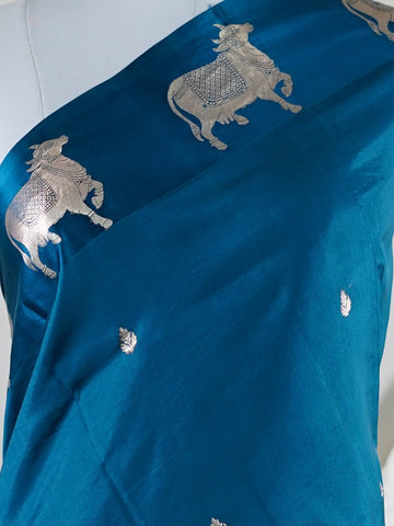 Katan A masterpiece from Varanasi, this Banarasi Katan saree in Dark Teal is a tribute to India's rich handloom legacy. The Tested Zari weaving and Motifs motifs make it a perfect choice for brides and celebrations. Every thread speaks of elegance, tradition, and the skilled hands that bring this saree to life. Sohinia - Banarasi Katan Silk Saree | Woven Motifs - Manoranjitham Weaves - Handloom Store
